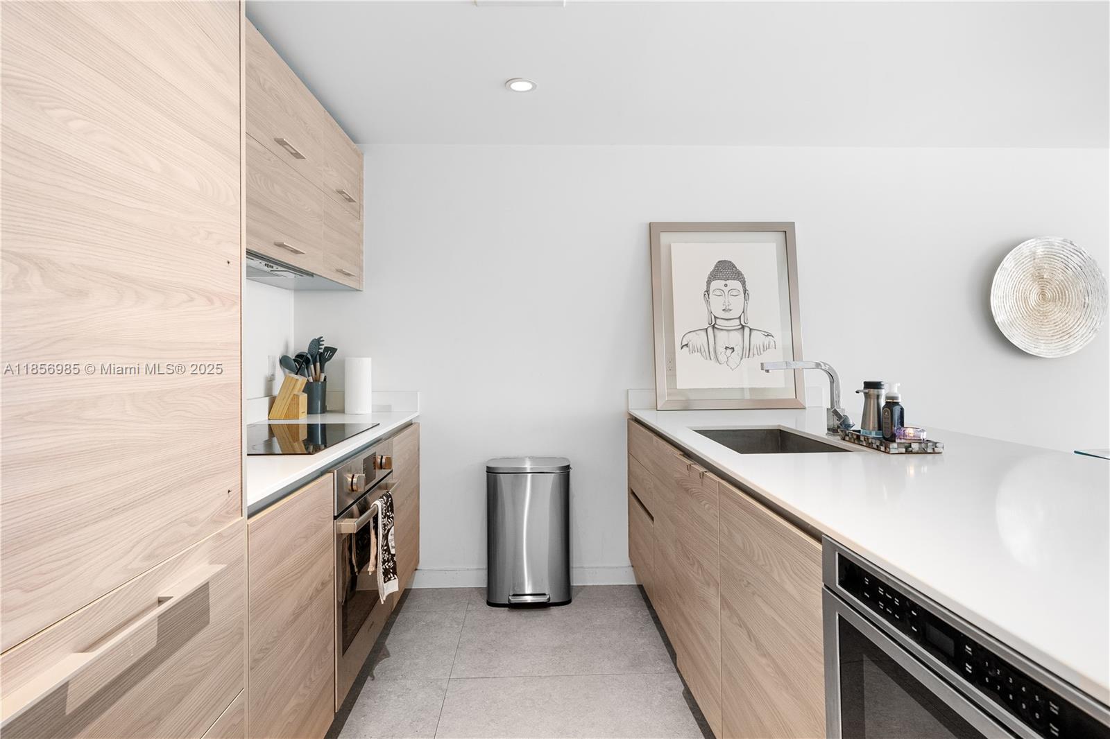 A modern galley kitchen features light wood cabinetry, white countertops, and stainless steel appliances — 1300 S Miami Ave # 2411, Miami FL 33130, MIAMI, FL