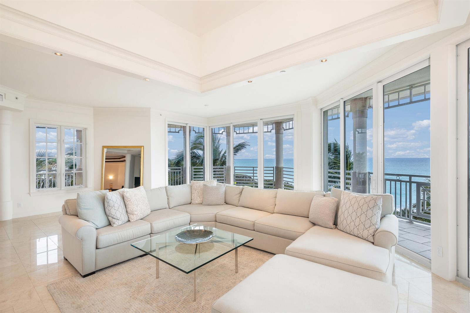 A bright living room features a large sectional sofa, glass coffee table, and ocean views — 120 Jupiter Key Road # 4, Jupiter FL 33477, JUPITER, FL