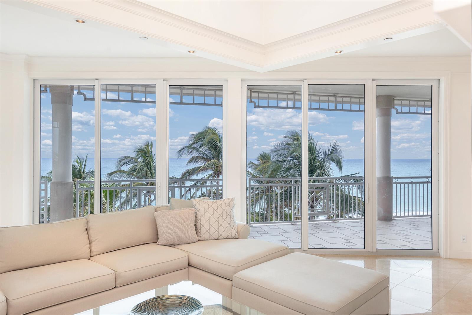 A living room with a beige sectional sofa faces large sliding glass doors overlooking the ocean — 120 Jupiter Key Road # 4, Jupiter FL 33477, JUPITER, FL