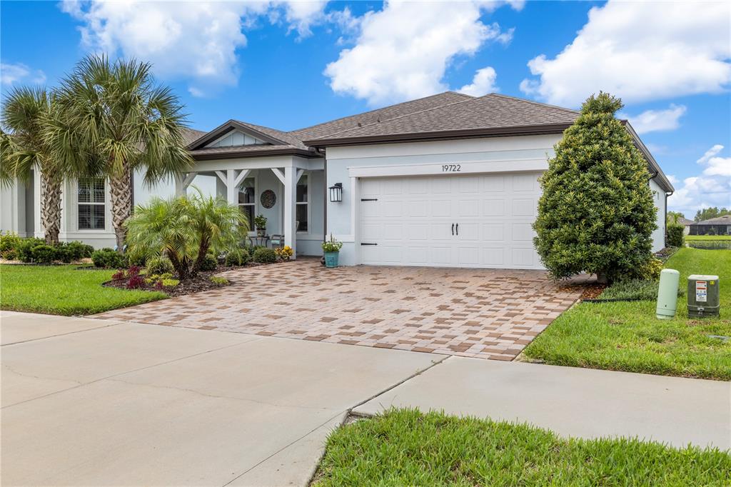 A single-story house with a white garage, paver driveway, and palm trees in the front yard — 19722 SEA GLASS CIRCLE, LAND O LAKES, FL