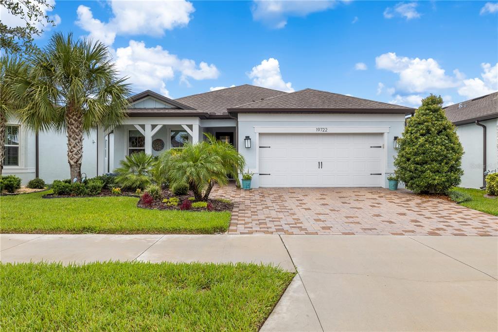 A single-story house with a white garage, paver driveway, and palm trees in the front yard — 19722 SEA GLASS CIRCLE, LAND O LAKES, FL