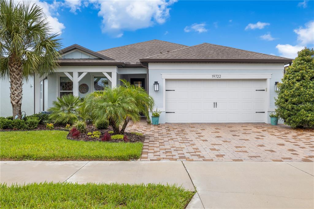 A single-story house features a white garage, a paved driveway, and a landscaped front yard — 19722 SEA GLASS CIRCLE, LAND O LAKES, FL