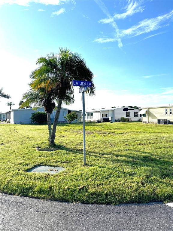 A street sign stands in a grassy lot near several manufactured homes under a blue sky — 602 LA JOLLA CIRCLE, NORTH PORT, FL