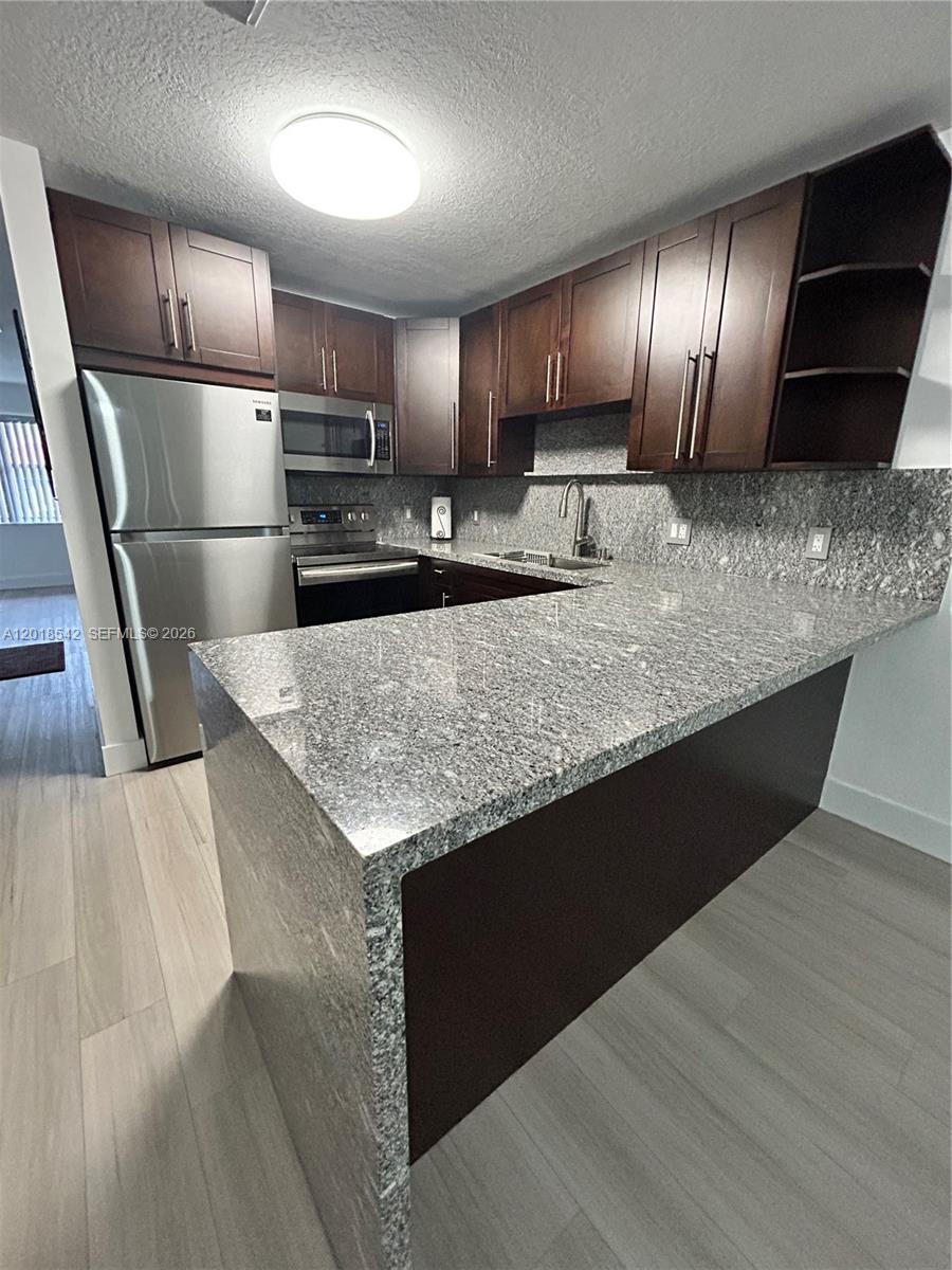 A kitchen features dark wood cabinets, granite countertops, and stainless steel appliances — 13884 SW 64th St, Miami FL 33183, MIAMI, FL