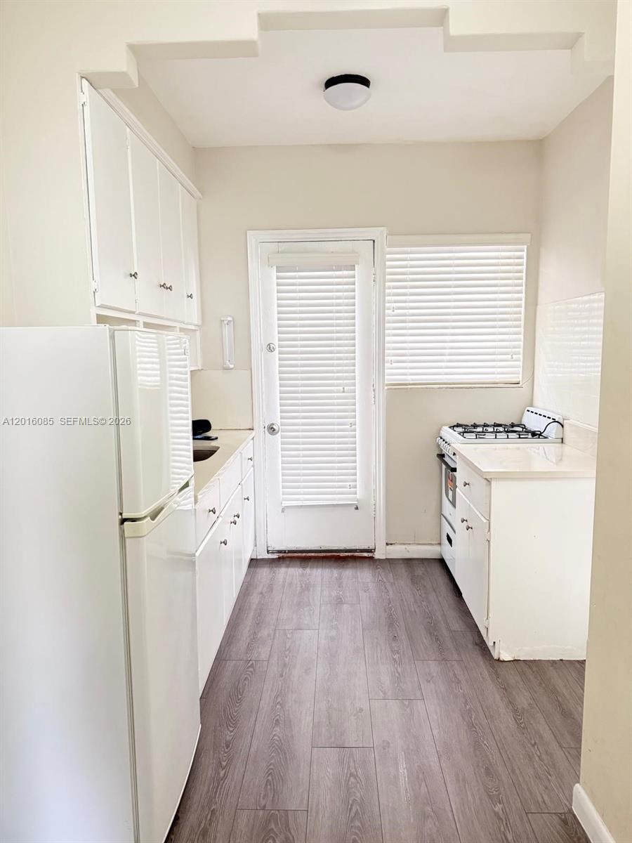 A narrow kitchen features white cabinets, a refrigerator, a gas stove, and wood-look flooring — 1007 Meridian Ave # 9, Miami Beach FL 33139, MIAMI BEACH, FL