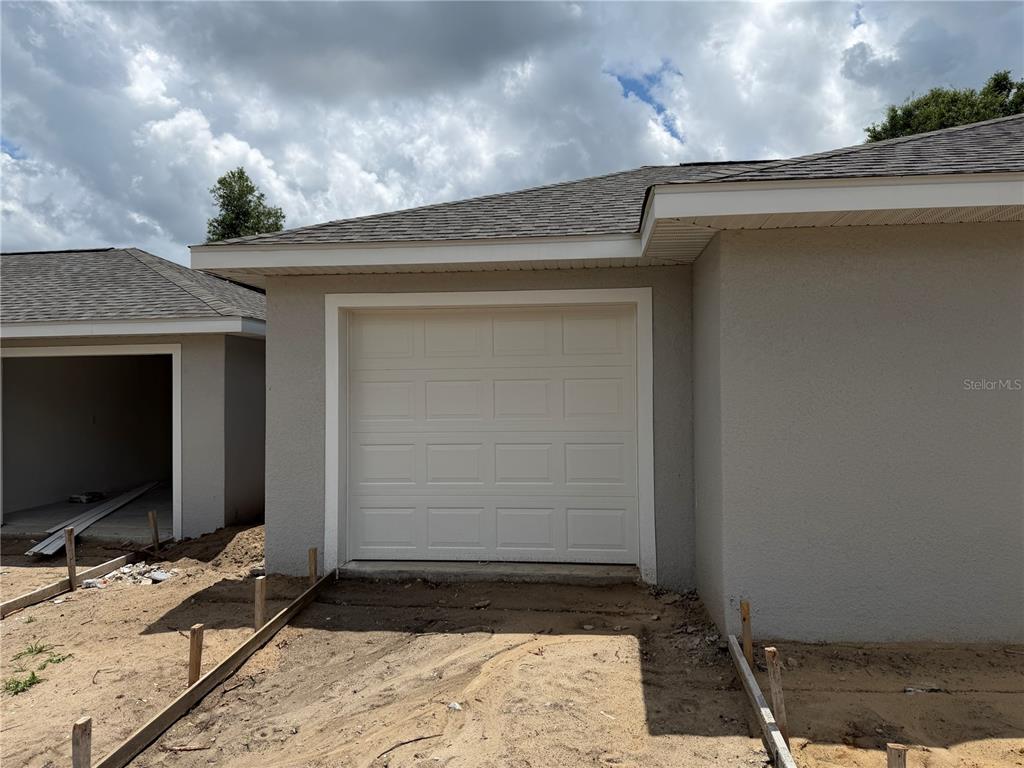An exterior view of a house under construction featuring a closed white garage door — 7640 SW 14TH STREET, OCALA, FL