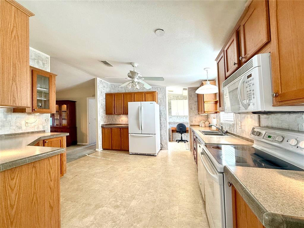 A kitchen features oak cabinets, white appliances, laminate countertops, and a ceiling fan — 250 S PORT ROYAL LANE, APOLLO BEACH, FL