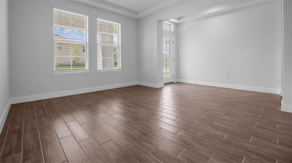 An empty room features light gray walls, wood-look tile flooring, and two windows — 11827 SHINE VIEW LANE, WINTER GARDEN, FL