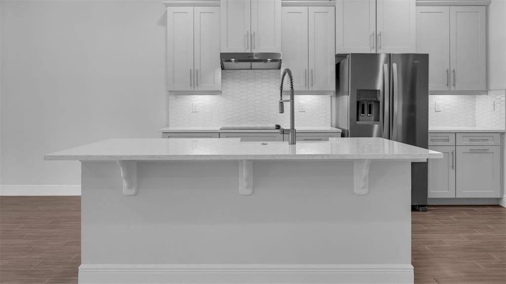 A modern kitchen features light gray cabinets, white quartz countertops, and a central island — 11827 SHINE VIEW LANE, WINTER GARDEN, FL