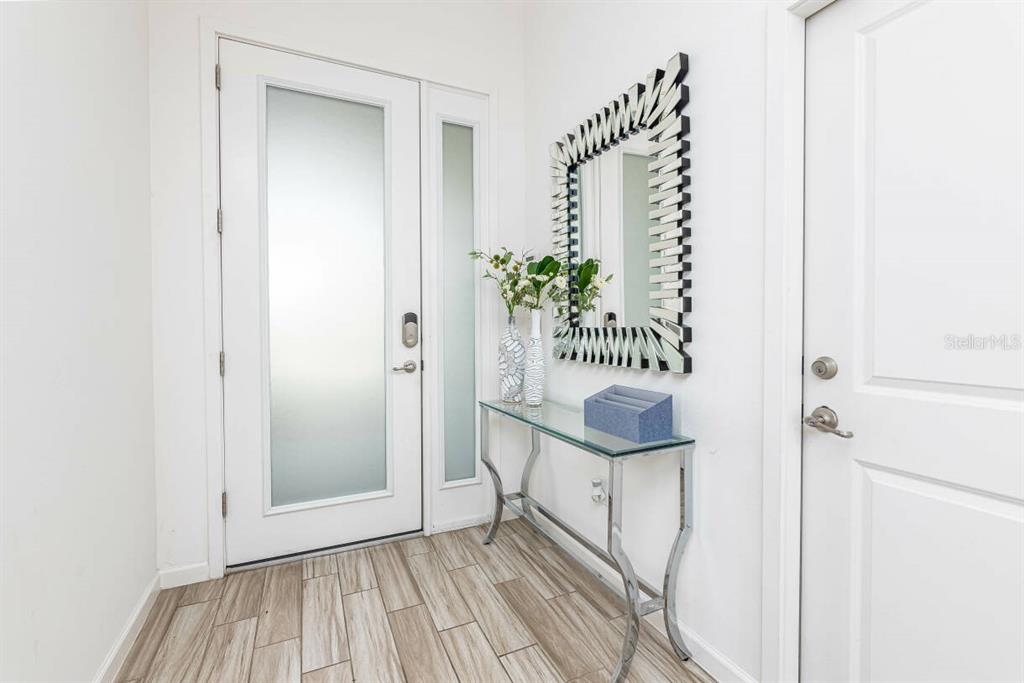 An entryway features a glass-paneled door, a console table, and a decorative wall mirror — 2678 CALISTOGA AVENUE, KISSIMMEE, FL