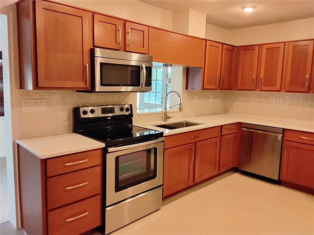 A kitchen features wood cabinets, stainless steel appliances, and white countertops — 2818 E MICHIGAN STREET, ORLANDO, FL