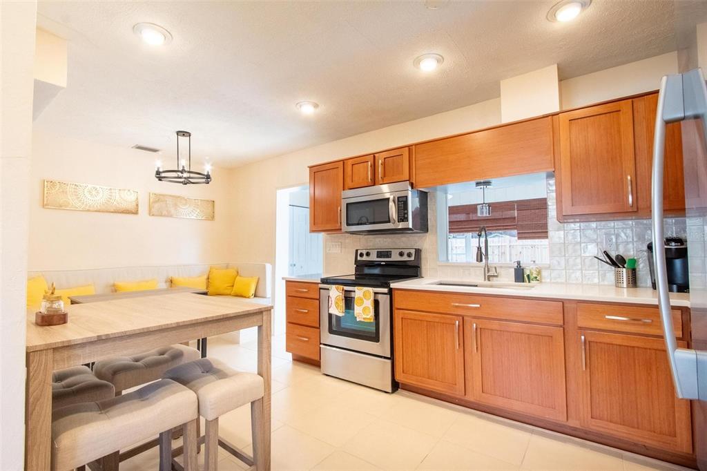 A kitchen with wood cabinets, stainless steel appliances, and an adjacent dining area with seating — 2818 E MICHIGAN STREET, ORLANDO, FL