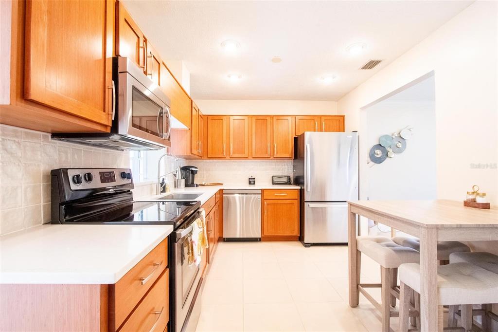 A kitchen with wood cabinets, stainless steel appliances, white countertops, and an adjacent dining area — 2818 E MICHIGAN STREET, ORLANDO, FL