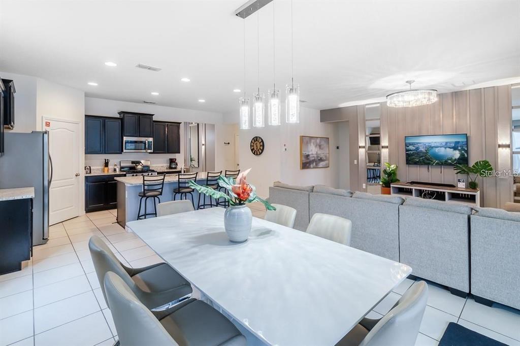 An open-concept living and dining area features a kitchen with dark cabinets and tile flooring — 6047 BROAD OAK DRIVE, DAVENPORT, FL