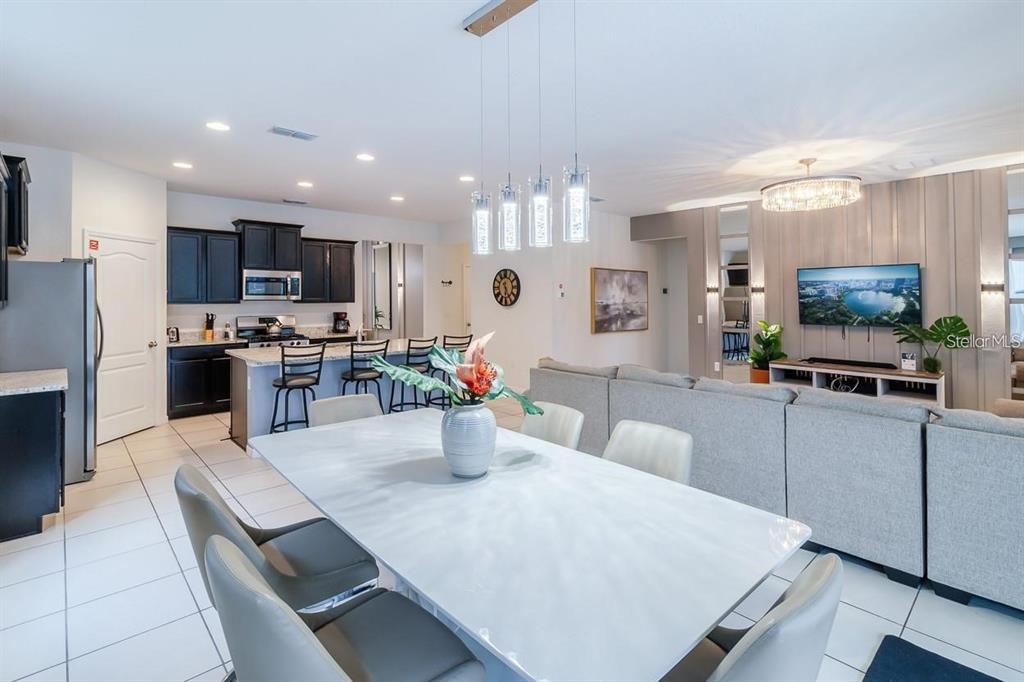 An open-concept living and dining area features a kitchen with dark cabinets and tile flooring — 6047 BROAD OAK DRIVE, DAVENPORT, FL