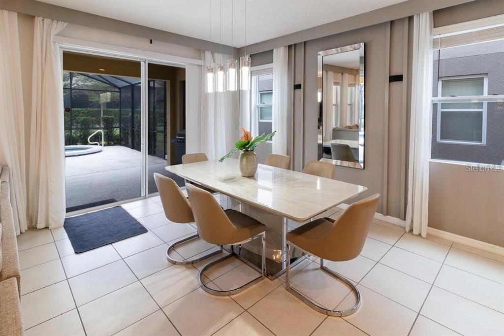 A dining room features a marble table, tan chairs, a tall mirror, and sliding glass doors — 6047 BROAD OAK DRIVE, DAVENPORT, FL