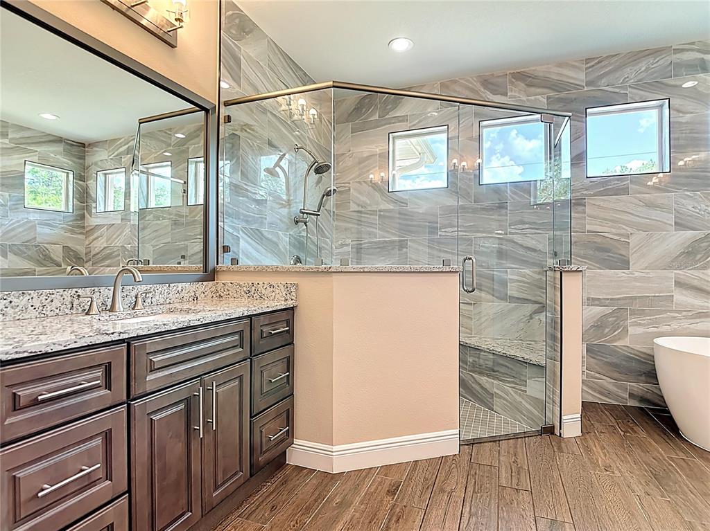 A bathroom features a dark wood vanity, granite countertops, and a glass-enclosed tiled shower — 19041 MARDI GRAS STREET, ORLANDO, FL