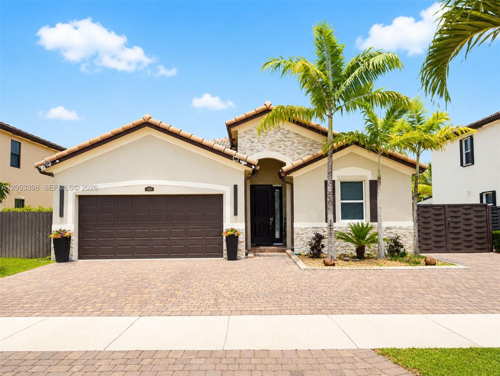 The exterior of a single-story house features a paved driveway, stone accents, and palm trees — 28151 SW 128th Path, Homestead FL 33033, HOMESTEAD, FL