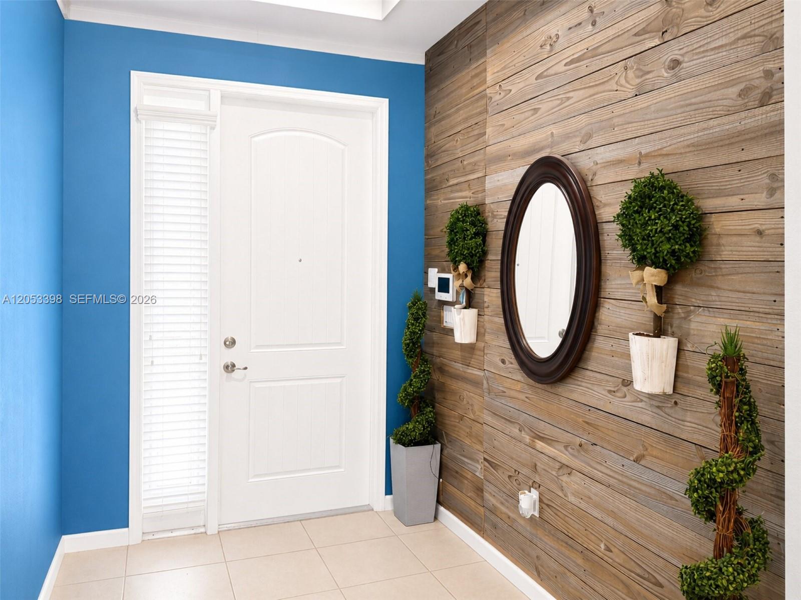 An entryway features a white door, blue walls, and a wood-paneled accent wall with decor — 28151 SW 128th Path, Homestead FL 33033, HOMESTEAD, FL