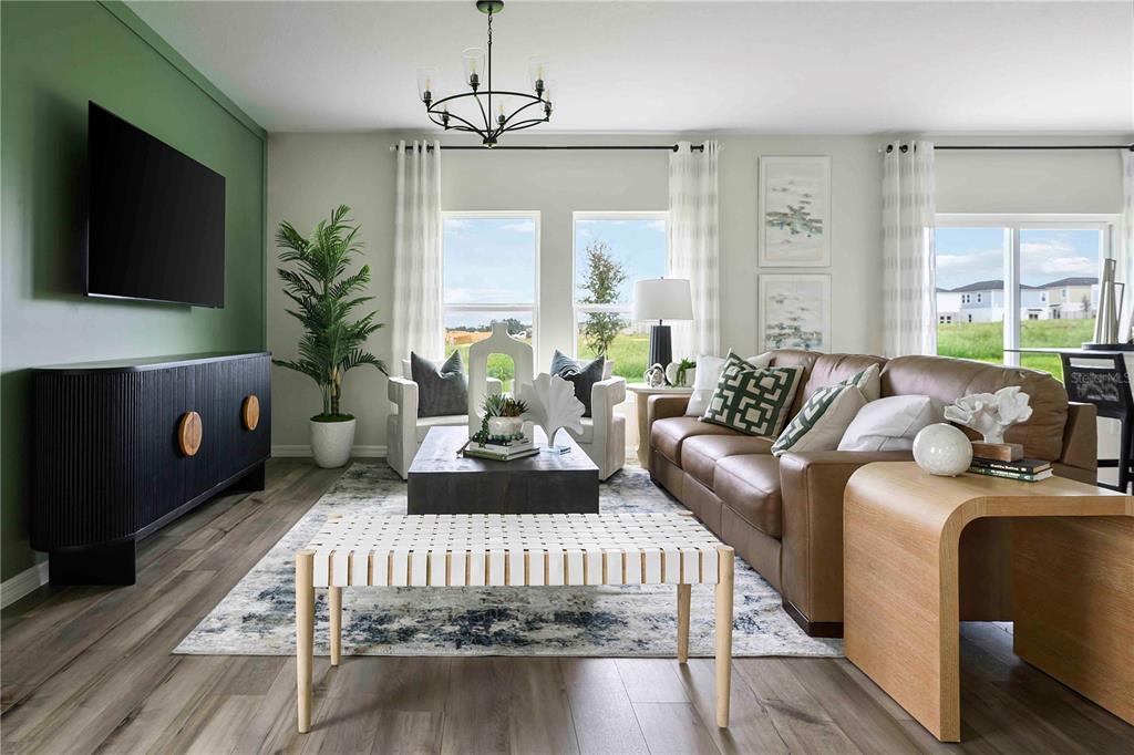 A living room features a green accent wall, brown leather sofa, and wood-look flooring — 2119 LAWSON WAY, ZEPHYRHILLS, FL