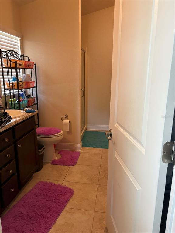 A bathroom features a vanity, a toilet with a purple cover, and a walk-in shower — 1131 ALLEGRO PLACE, DUNDEE, FL