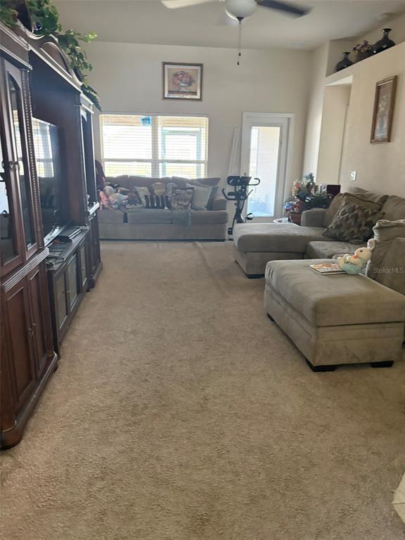 A living room features a large entertainment center, beige carpeting, and two sectionals — 1131 ALLEGRO PLACE, DUNDEE, FL