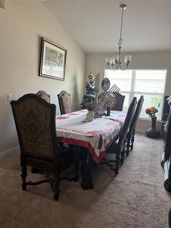 A dining room features a long table with chairs, a chandelier, and a window — 1131 ALLEGRO PLACE, DUNDEE, FL