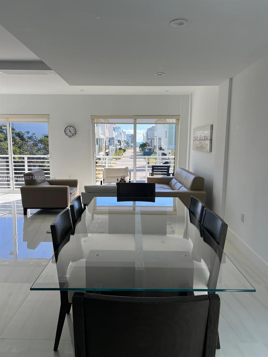 A dining area with a glass table overlooks a living room and a coastal street — 94825 Overseas Highway, Key Largo FL 33037, KEY LARGO, FL