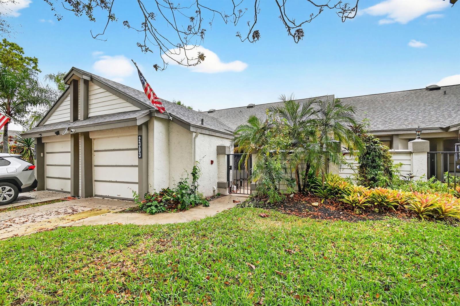 A single-story house with a two-car garage, a gated courtyard entrance, and a grassy lawn — 2303 Landings Boulevard, FL 33413, FL