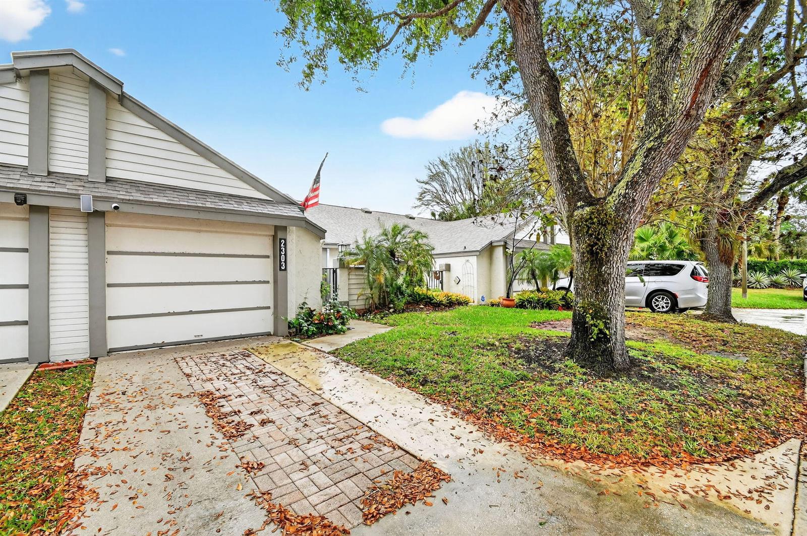 A single-story house with a white garage, paved driveway, and a large tree in front — 2303 Landings Boulevard, FL 33413, FL