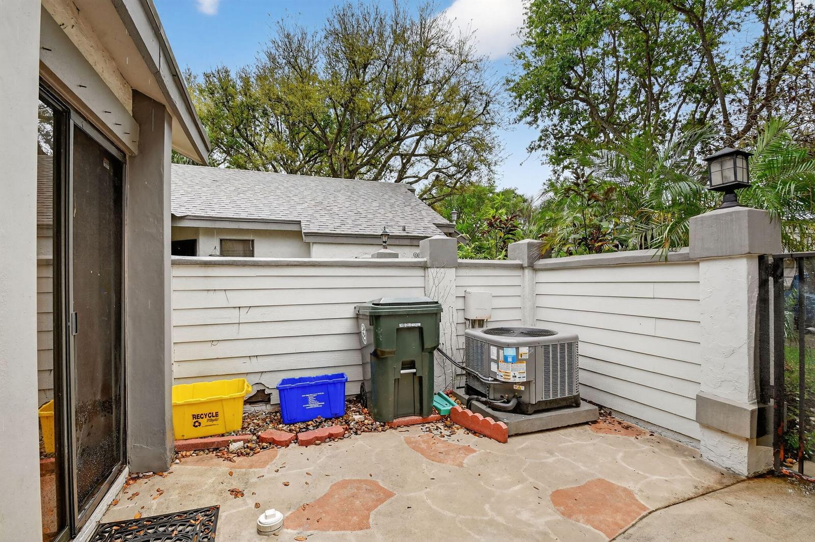 A patio area features a white fence, an air conditioning unit, and several trash bins — 2303 Landings Boulevard, FL 33413, FL