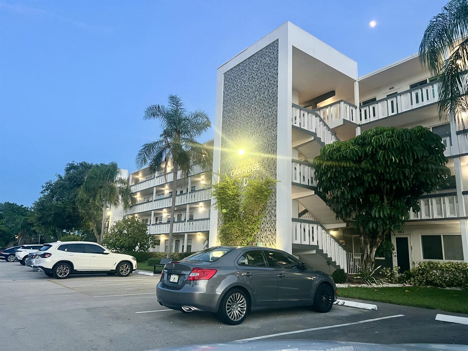 A gray sedan is parked in front of a multi-story apartment building labeled Oakridge D — 2026 Oakridge D, Deerfield Beach FL 33442, DEERFIELD BEACH, FL