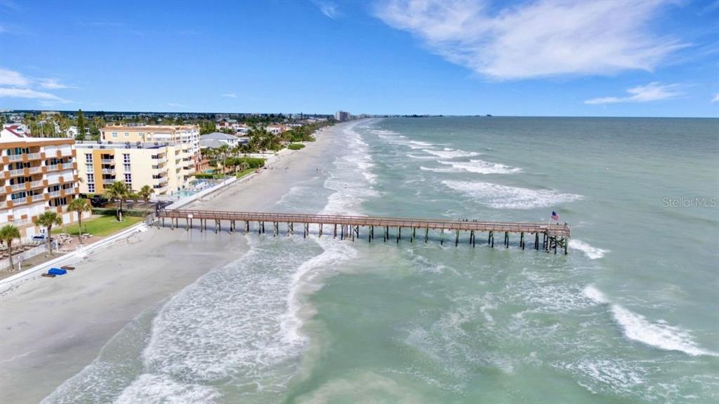 An aerial view shows a long wooden pier extending from a sandy beach into the ocean — 16333 GULF BOULEVARD UNIT 215, REDINGTON BEACH, FL