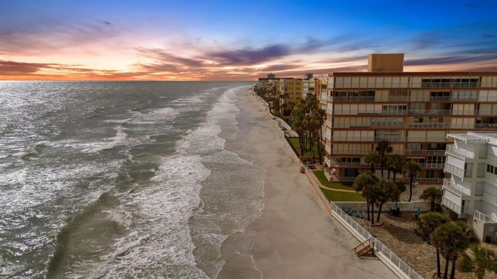 An aerial view of a sandy beach coastline with multi-story residential buildings at sunset — 16333 GULF BOULEVARD UNIT 215, REDINGTON BEACH, FL