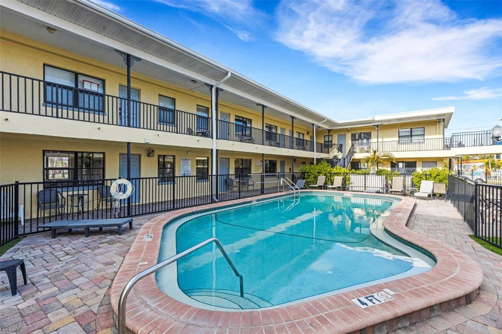 A two-story motel building features a central swimming pool with a brick-paved deck — 16333 GULF BOULEVARD UNIT 215, REDINGTON BEACH, FL