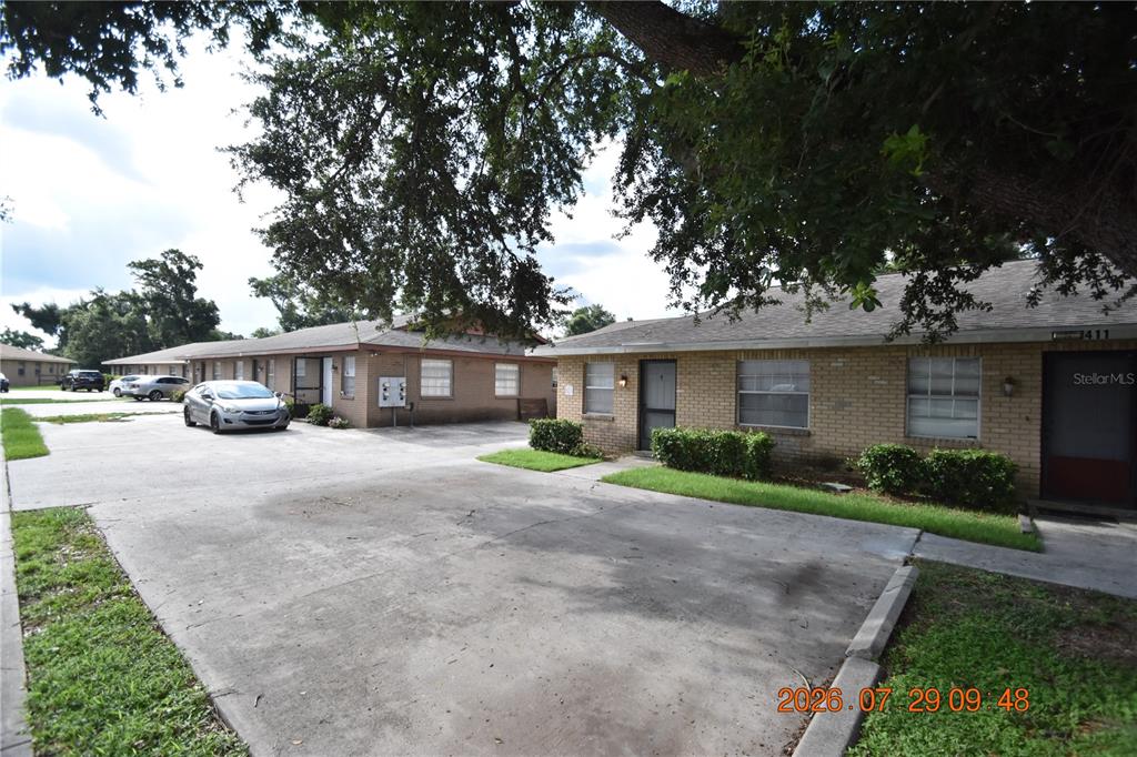 A single-story brick apartment building with a concrete parking lot and large shade trees — 411 BIG CEDAR WAY UNIT A, BRANDON, FL