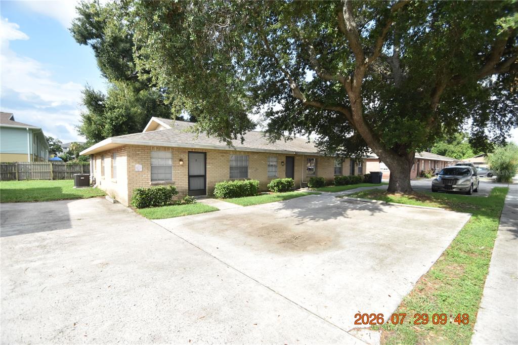 A single-story brick apartment building with a concrete parking area and a large oak tree — 411 BIG CEDAR WAY UNIT A, BRANDON, FL