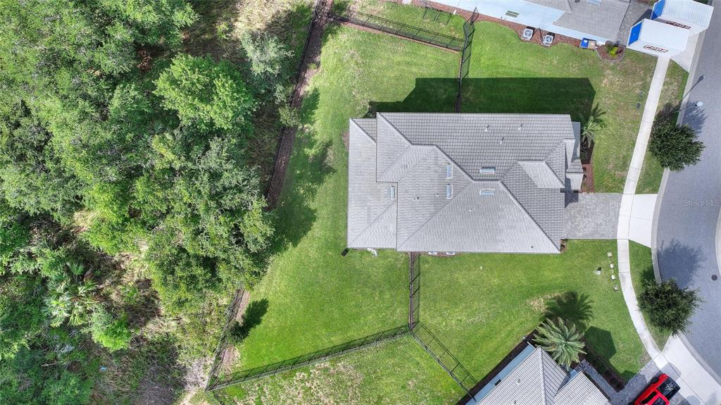 An aerial view shows a house with a gray roof, a fenced yard, and surrounding trees — 1455 OLYMPIC CLUB BOULEVARD, CHAMPIONS GATE, FL