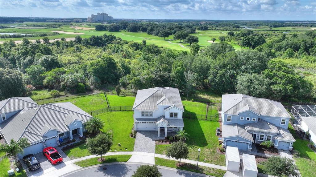 An aerial view shows three suburban houses with tiled roofs and driveways bordering a golf course — 1455 OLYMPIC CLUB BOULEVARD, CHAMPIONS GATE, FL