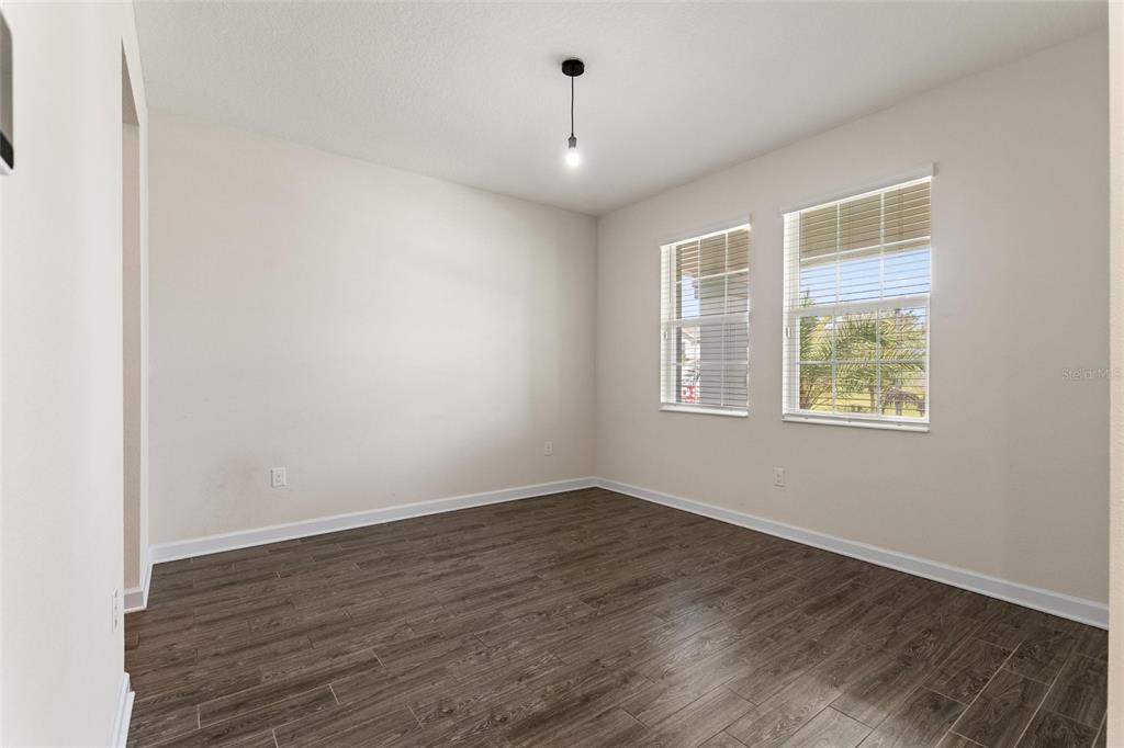 An empty room with wood-look tile flooring, white walls, and two windows with blinds — 1455 OLYMPIC CLUB BOULEVARD, CHAMPIONS GATE, FL