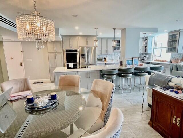 A kitchen with gray cabinetry and a breakfast bar opens to a dining area — 2860 S Ocean Boulevard # 301, Palm Beach FL 33480, PALM BEACH, FL