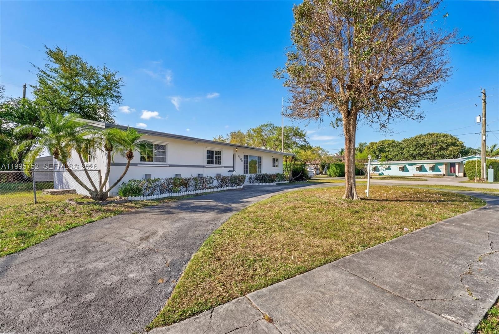 A single-story white house with a paved driveway and a large tree in the yard — 11190 SW 57th St, Miami FL 33173, MIAMI, FL