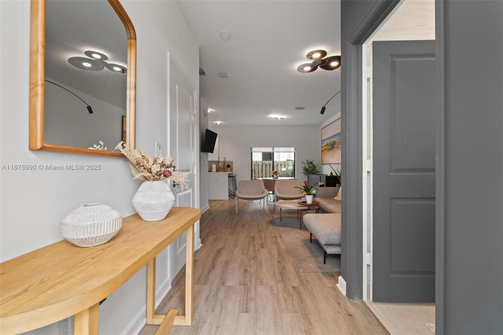A wooden console table sits in a hallway leading to an open-concept living area — 403 NE 212th St, Miami FL 33179, MIAMI, FL