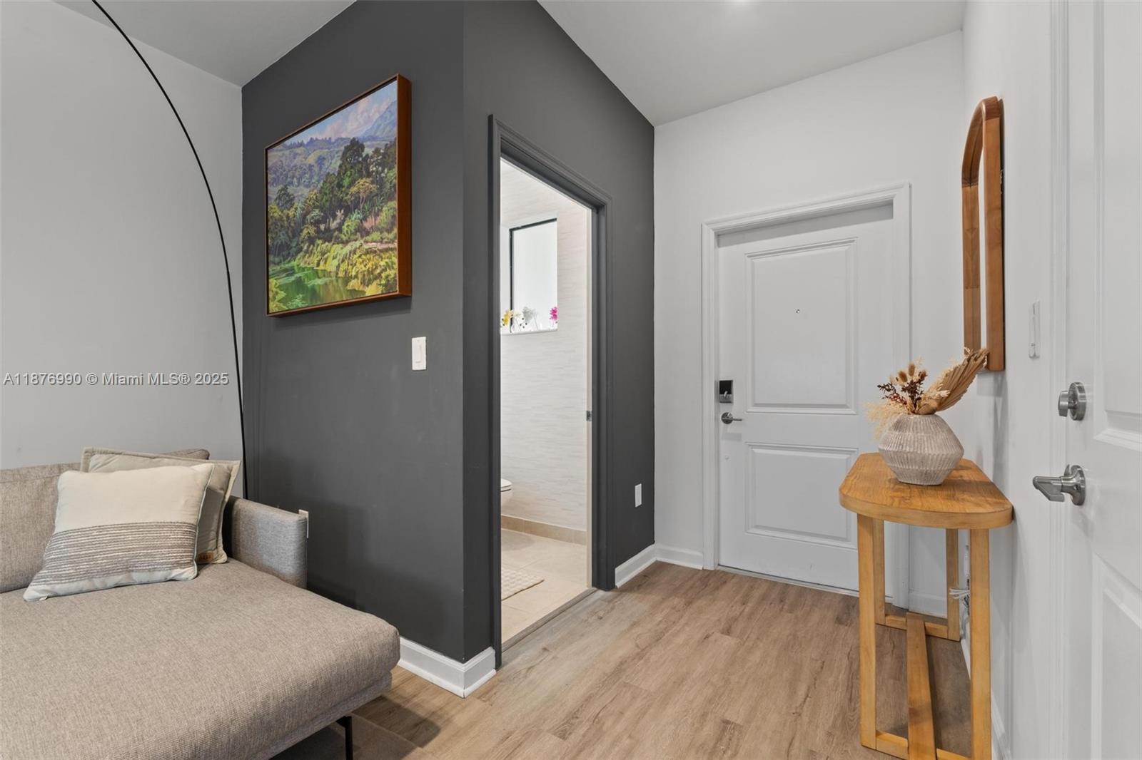 A gray sofa sits near a dark accent wall, a doorway, and a wooden console table — 403 NE 212th St, Miami FL 33179, MIAMI, FL