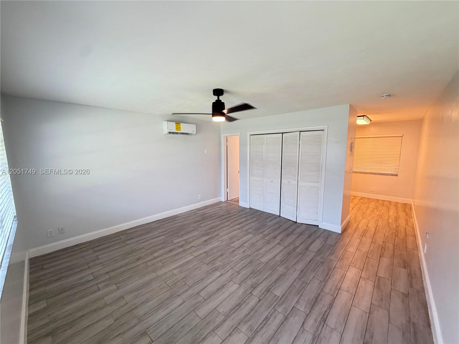 A room with light gray walls, wood-look tile flooring, a ceiling fan, and louvered closets — HOLLYWOOD, FL