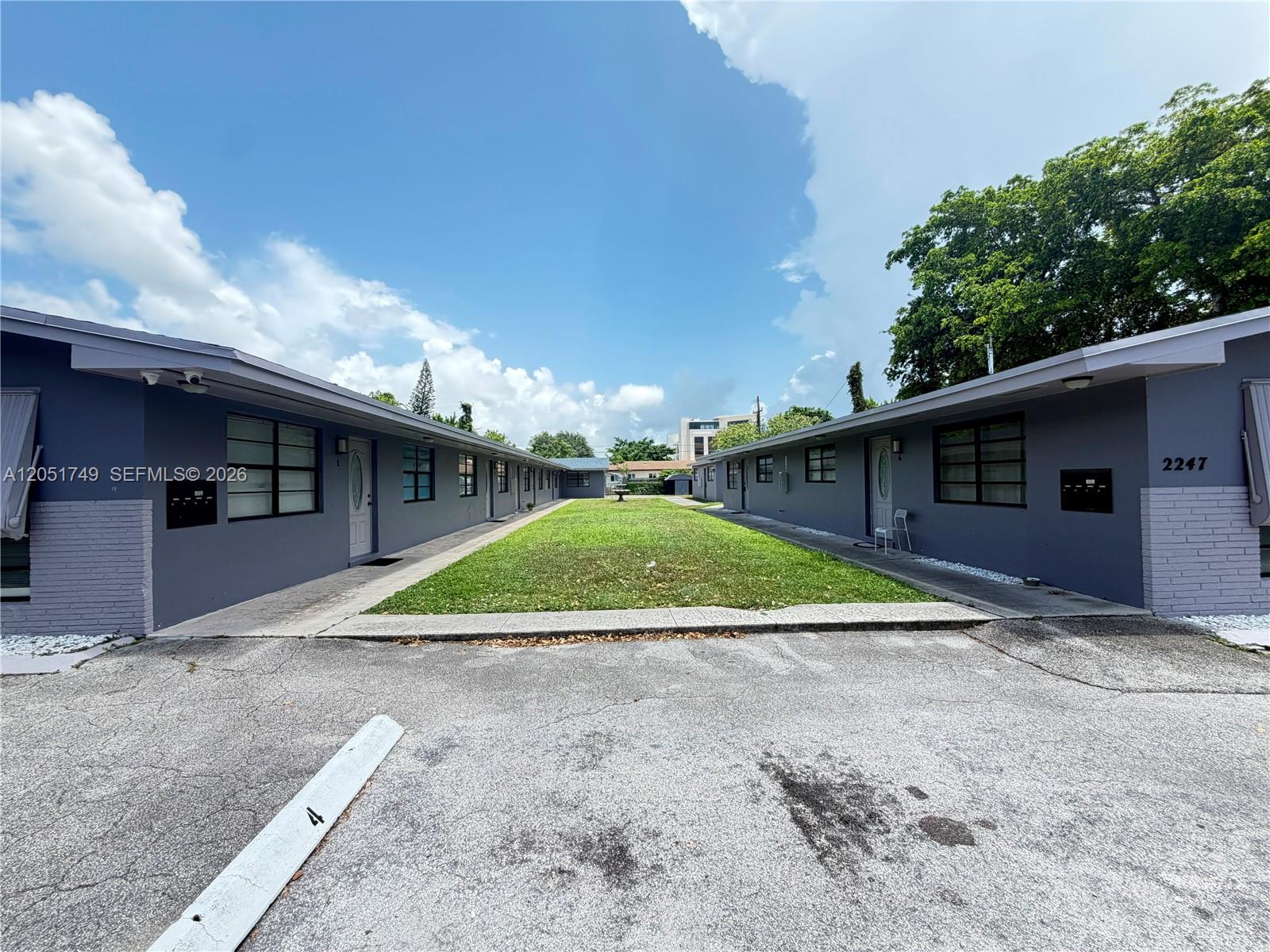 Two gray apartment buildings face each other across a central grassy courtyard — HOLLYWOOD, FL