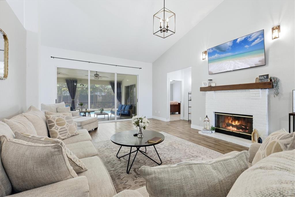 A living room features a white brick fireplace, vaulted ceilings, and sliding glass doors — 9114 16TH AVENUE CIRCLE NW, BRADENTON, FL