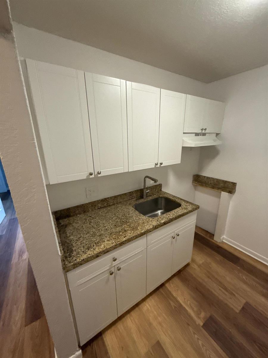 A small kitchenette features white cabinets, a granite countertop, and a stainless steel sink — 717 NE 10th Avenue # 06, Boynton Beach FL 33435, BOYNTON BEACH, FL