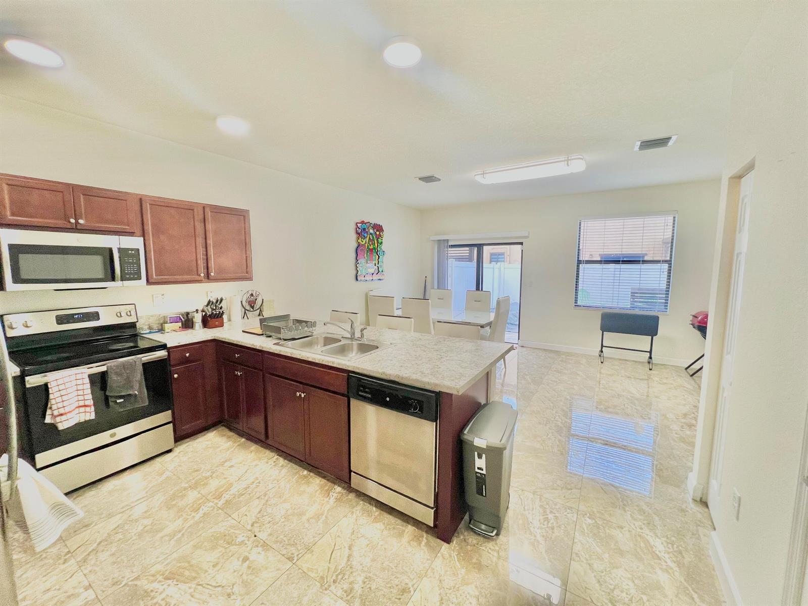 A kitchen with dark wood cabinets, stainless steel appliances, and light-colored tile flooring — 10490 W 33rd Way, Hialeah FL 33018, HIALEAH, FL