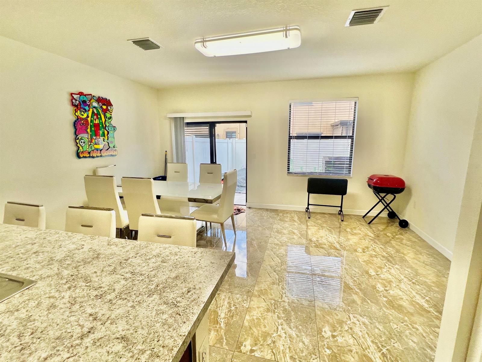 A dining area features a white table, matching chairs, marble-look tile floors, and a sliding door — 10490 W 33rd Way, Hialeah FL 33018, HIALEAH, FL